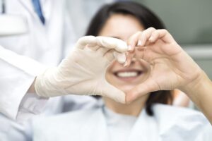 Patient and doctor creating a heart from hands after successful dental treatment in Kanata, ON