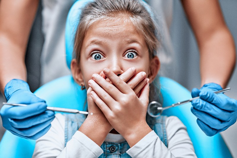 Young girl scared at the dentist covering her mouth in Stittsville and Kanata, ON