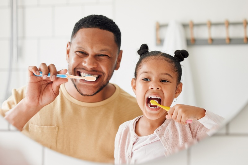 Father and daughter brushing their teeth together to maintain healthy oral hygiene and prevent cavities in Kanata and Stittsville, ON