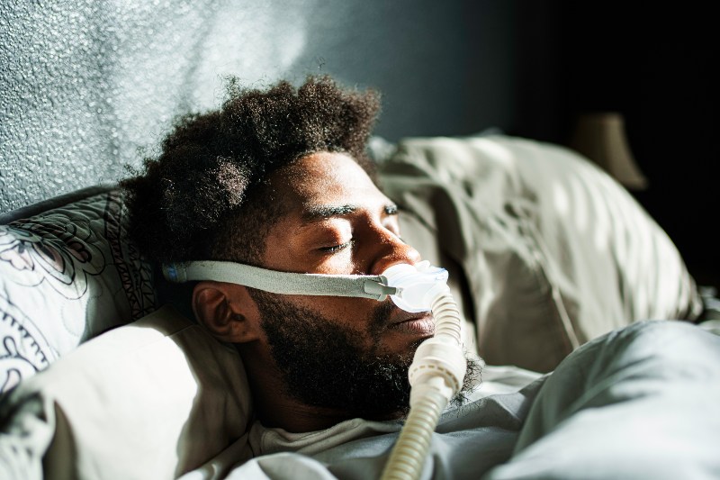 Man wearing a CPAP machine while sleeping to treat sleep apnea and improve breathing during the night in Kanata and Stittsville, ON